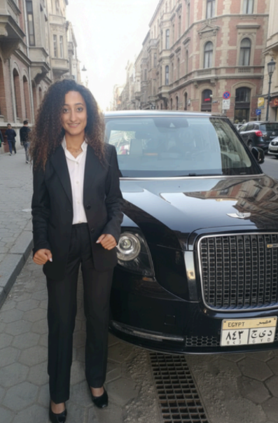 Woman stands in front of an electric London black cab