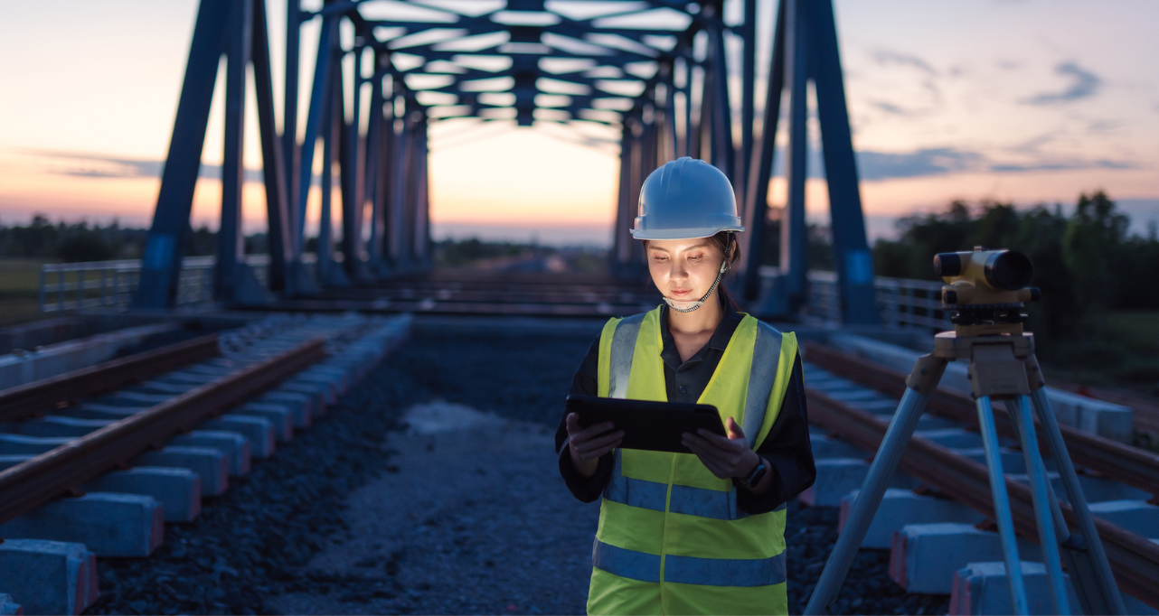 Engineer inspecting railway bridge infrastructure using digital equipment.
