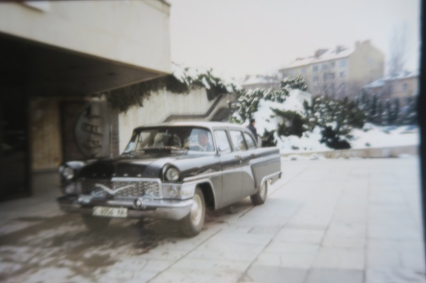 Vintage car parked outside a building on a snowy day.