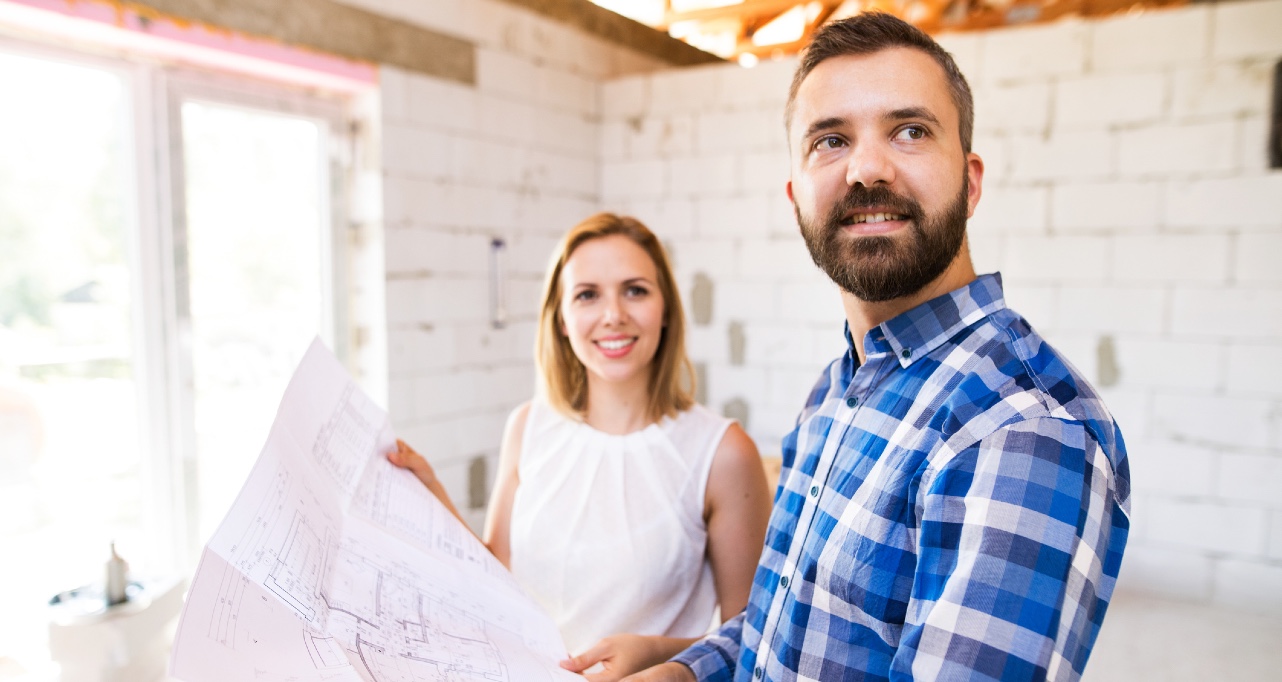 Young couple at the construction site. A man and woman looking at plans of the new house, discussing issues at the construction site.
