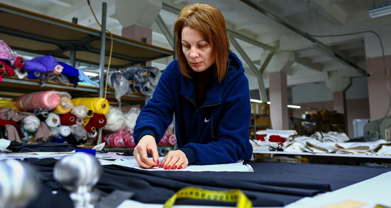 SME worker in Ukraine measuring fabric on a production table