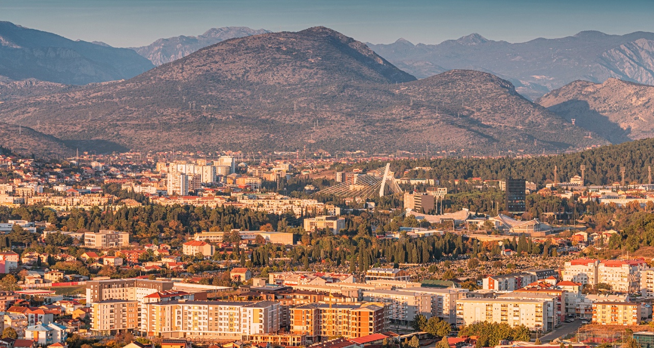 Elevated view of Podgorica, capital of Montenegro, featuring the Millennium Bridge, modern architecture, and the Dinaric Alps