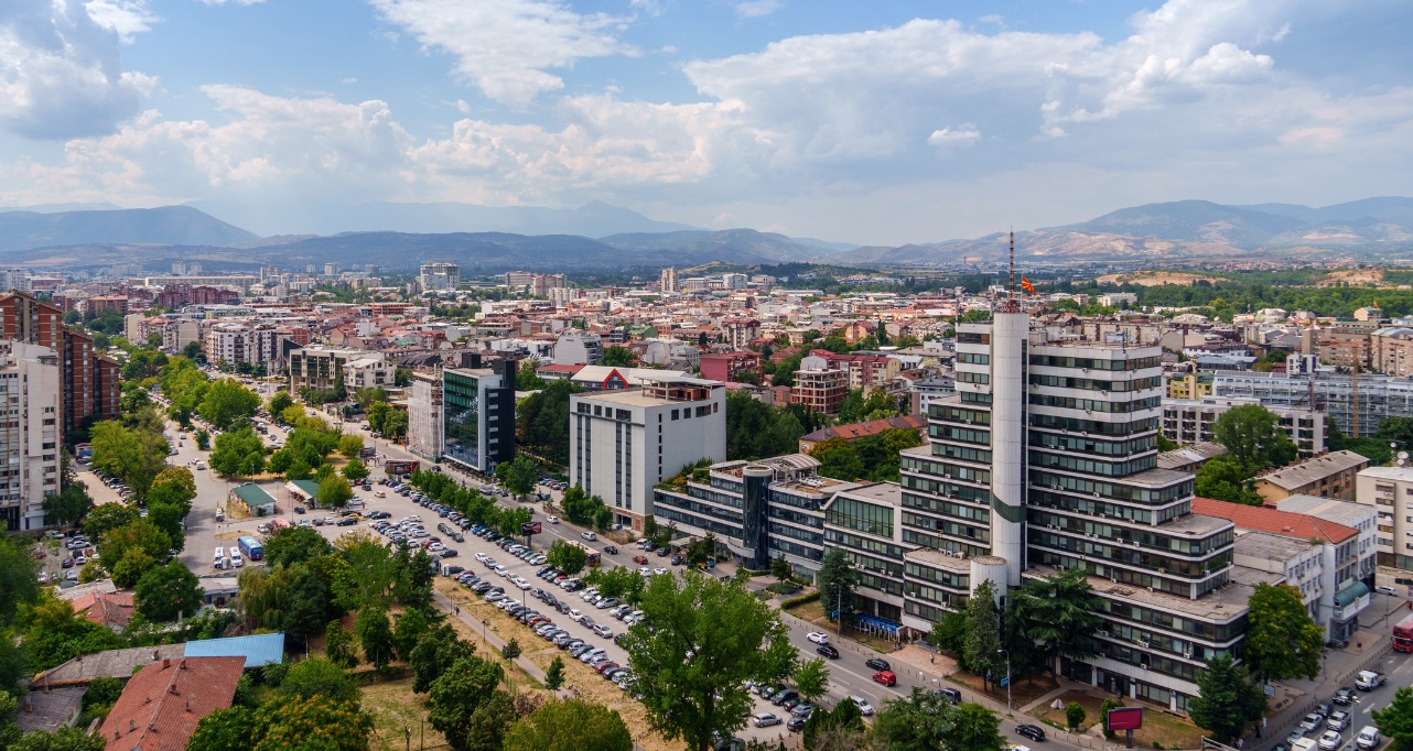 Skopje Macedonia urban cityscape under a bright cloudy sky with mountains on the horizon