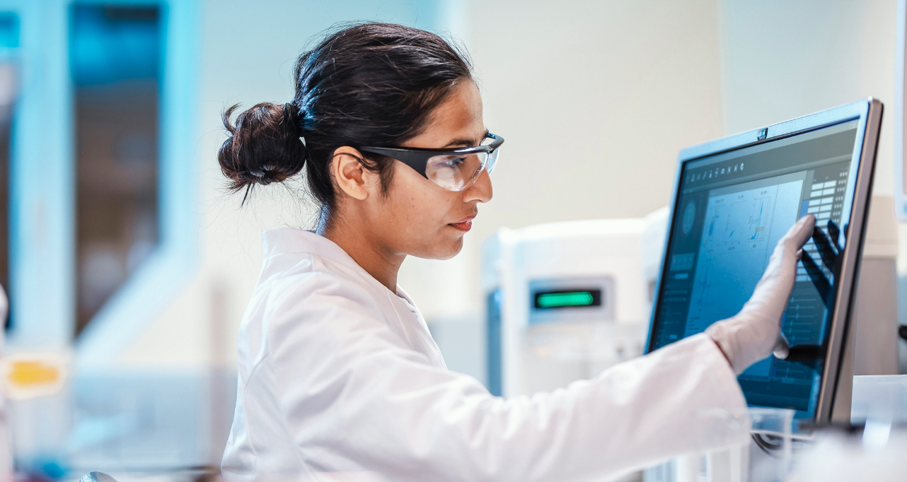 Woman in lab coat touching screen