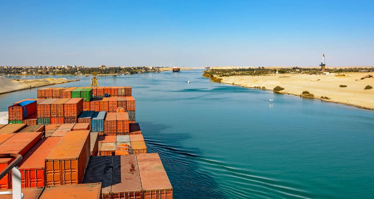 Industrial container ship passing through Suez Canal with ship's convoy, view on the bow from the captain bridge