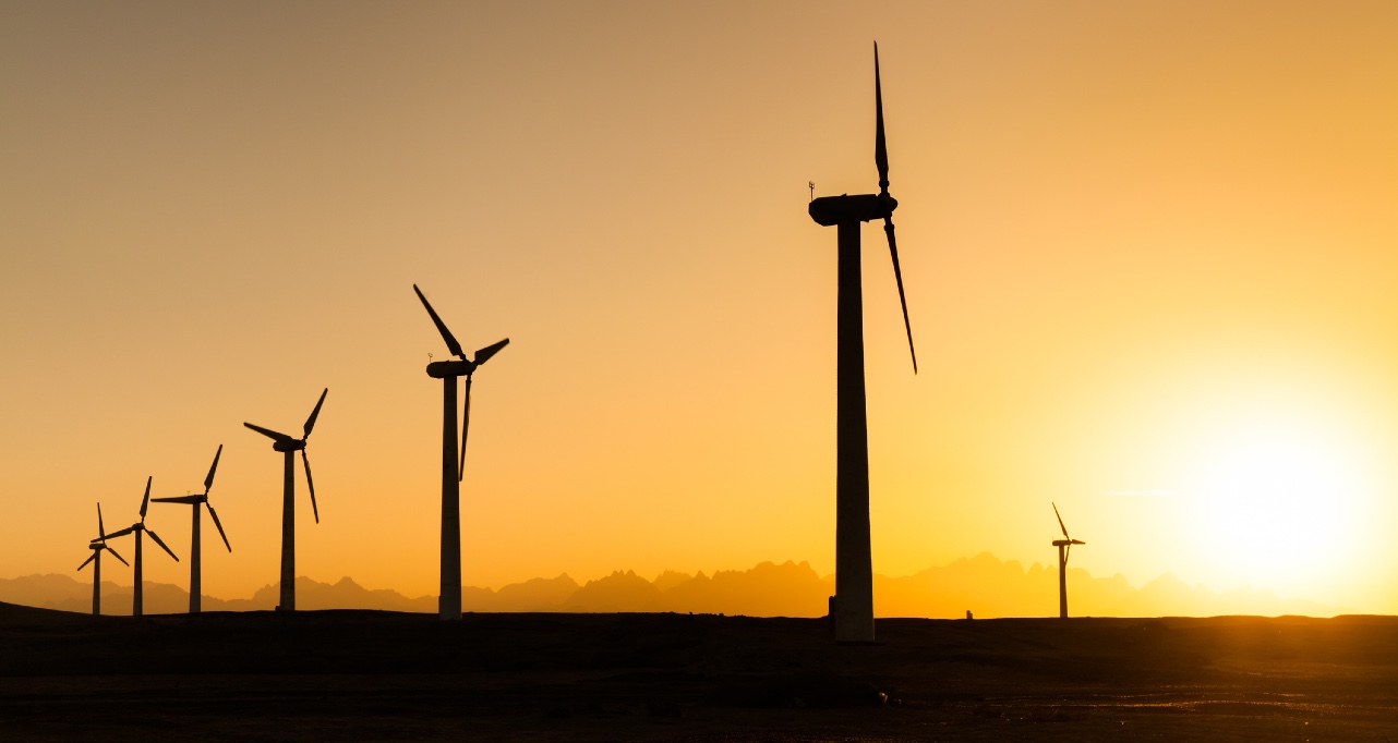 Big wind turbines in the desert at sunset background
