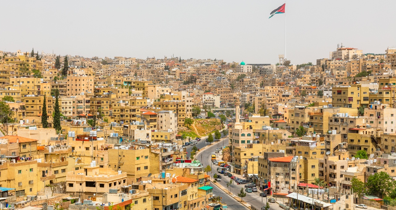 Lots of residential houses densily scattered on the hills in the downtown of Amman city with national flag waving on the wind, Kingdom of Jordan