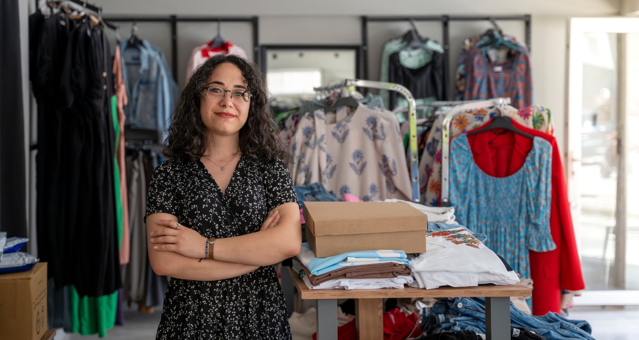 Successful small business owner young woman in casual clothing standing at entrance and looking at camera.