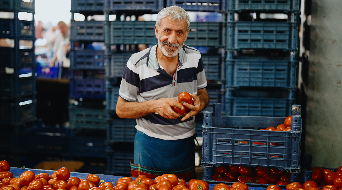 Men holding tomatoes standing in market
