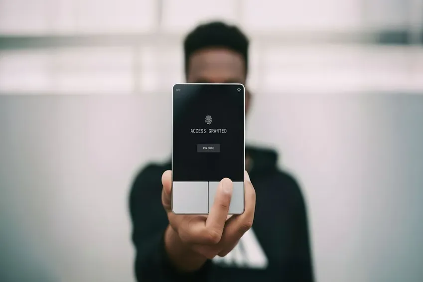 Person holding a biometric access device displaying a fingerprint icon and “Access Granted.